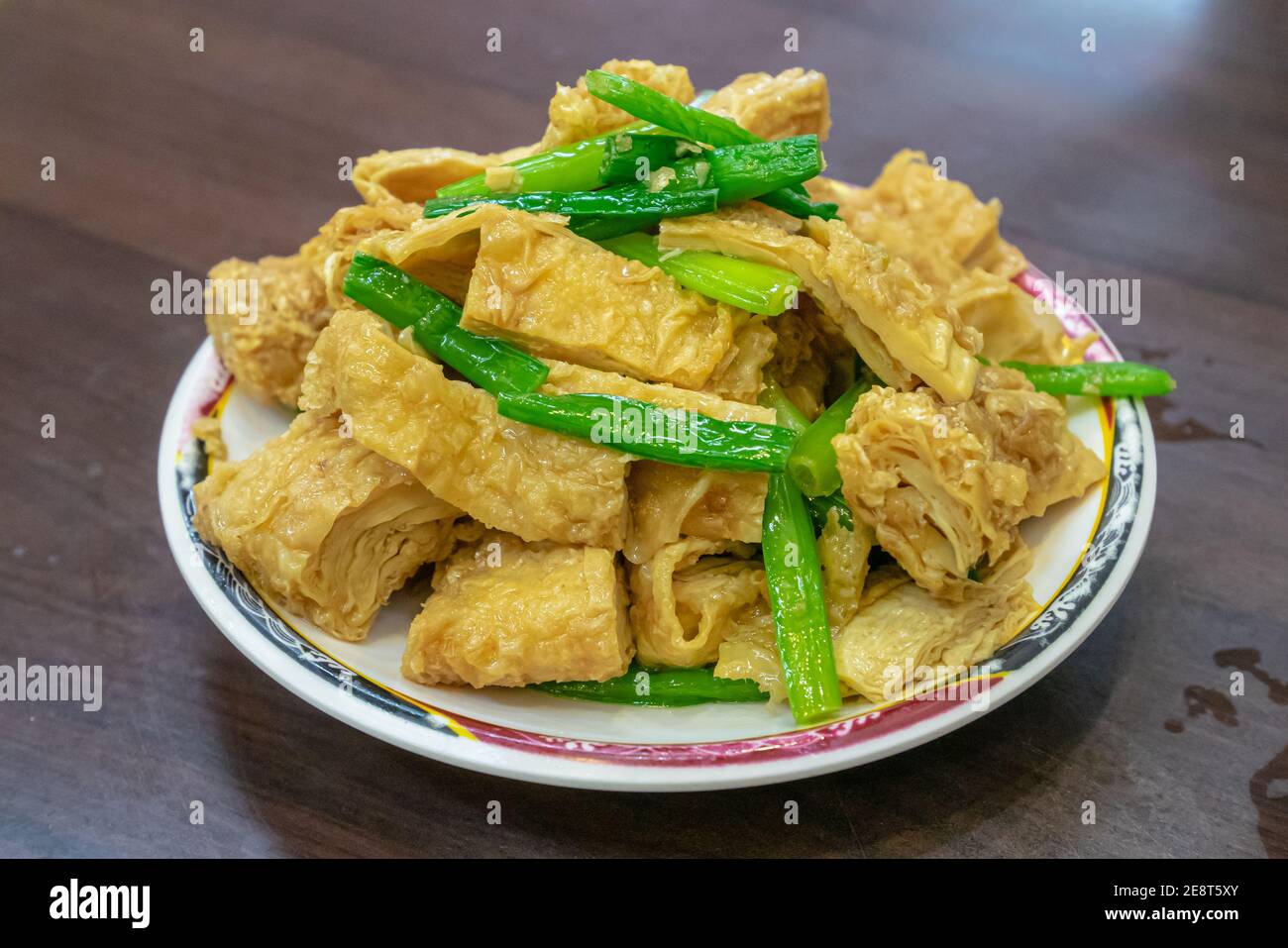 Eine Nahaufnahme von Taiwan traditionelle rühren gebratene Tofu Haut (Bohnenkerze Blatt), taiwanesische Essen auf Holztisch im Restaurant in Taiwan Nachtmarkt. Stockfoto