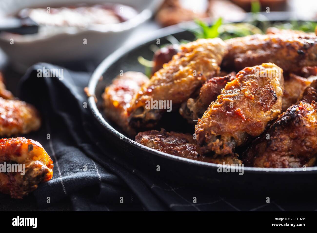 Hähnchenflügel Grillen Sie in einer gusseisernen Auflaufform mit BBQ-Sauce und Rosmarin Stockfoto