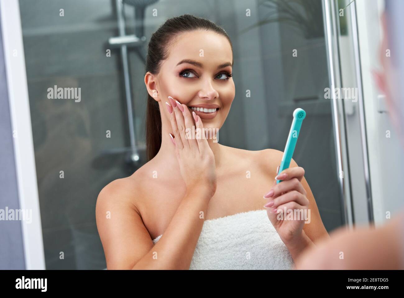Frau auf der Suche nach Reflexion im Spiegel nach dem Duschen Stockfoto