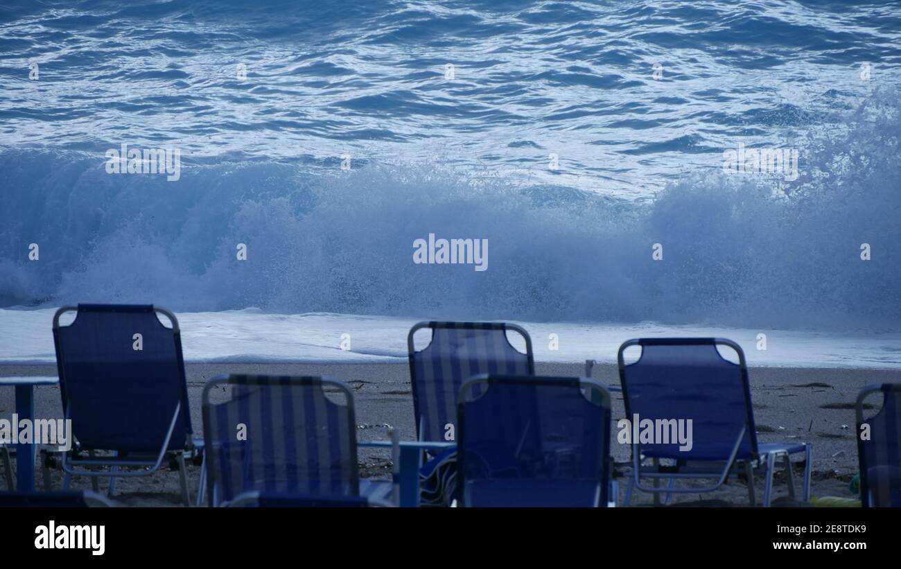 Blaues Meerwasser mit weißen Wellen und Sonnenbetten am Strand. Sommerurlaub. Stockfoto