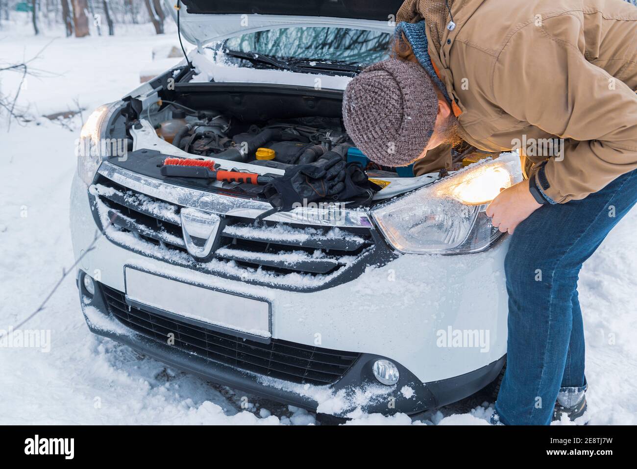 Motorhaube geöffnet. Der Fahrer überprüft nach starkem Schneefall bei sehr kaltem Wetter Motor, Flüssigkeit und Licht. Schlechtes Wetter zum Fahren. Verkehrssicherheit Stockfoto