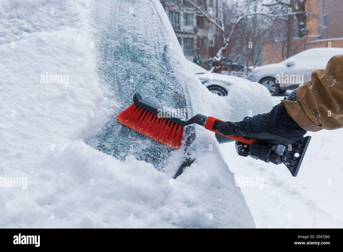 Hand mit einer Bürste Reinigung Auto Windschutzscheibe von Schnee. Fahren im Winter Stockfoto