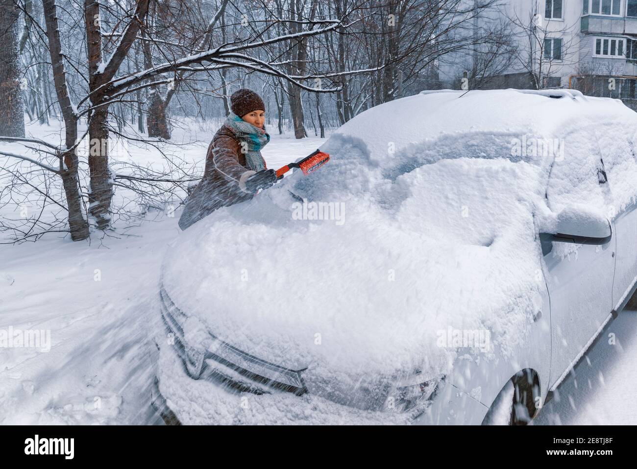 Die Fahrerin reinigt die Windschutzscheibe ihres Autos von Schnee. Auto fahren im Winter Stockfoto