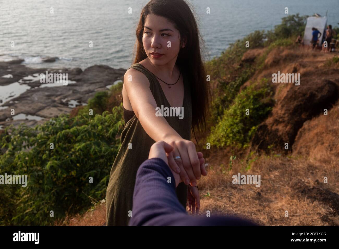 Aufnahme einer jungen Frau, die jemanden an der Hand am Strand führt Stockfoto