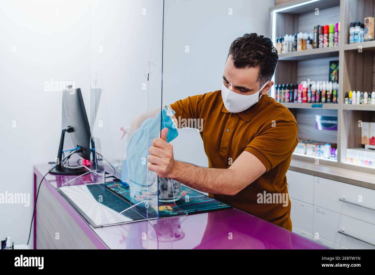 Einzelhandelsmanager bei der Reinigung von Schutzglas während einer Viruspandemie Stockfoto