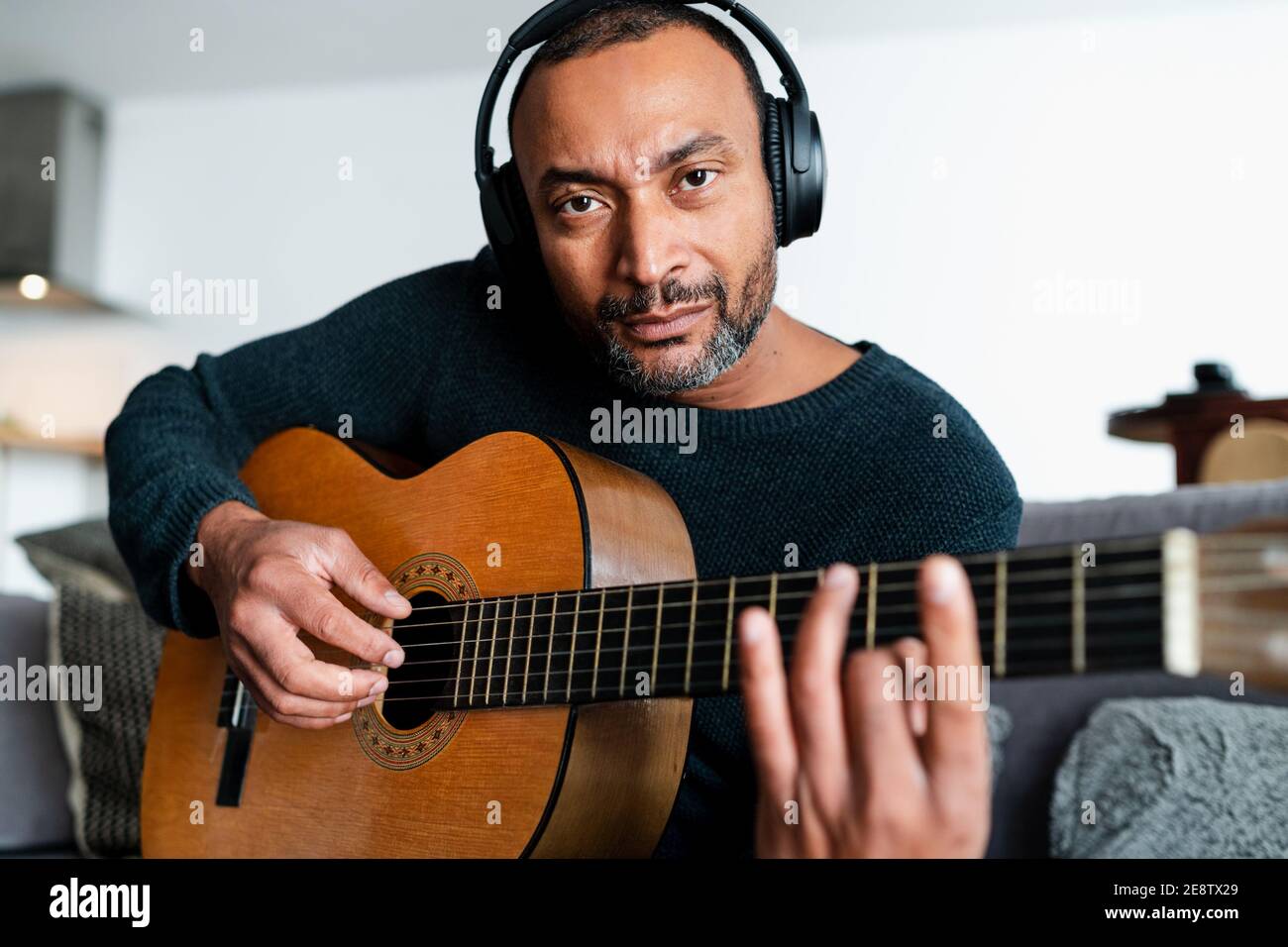 40 Jahre alter Mann, der Gitarre mit Online-Unterricht lernt Zu Hause Stockfoto