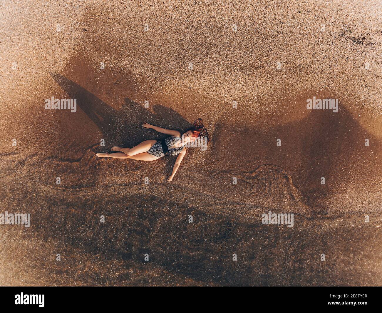Junge Frau mit roten Haaren in einem Badeanzug liegt Im klaren Küstenwasser des Meeres mit einem Sandy Bottom Drone View Shooting Drohne Stockfoto