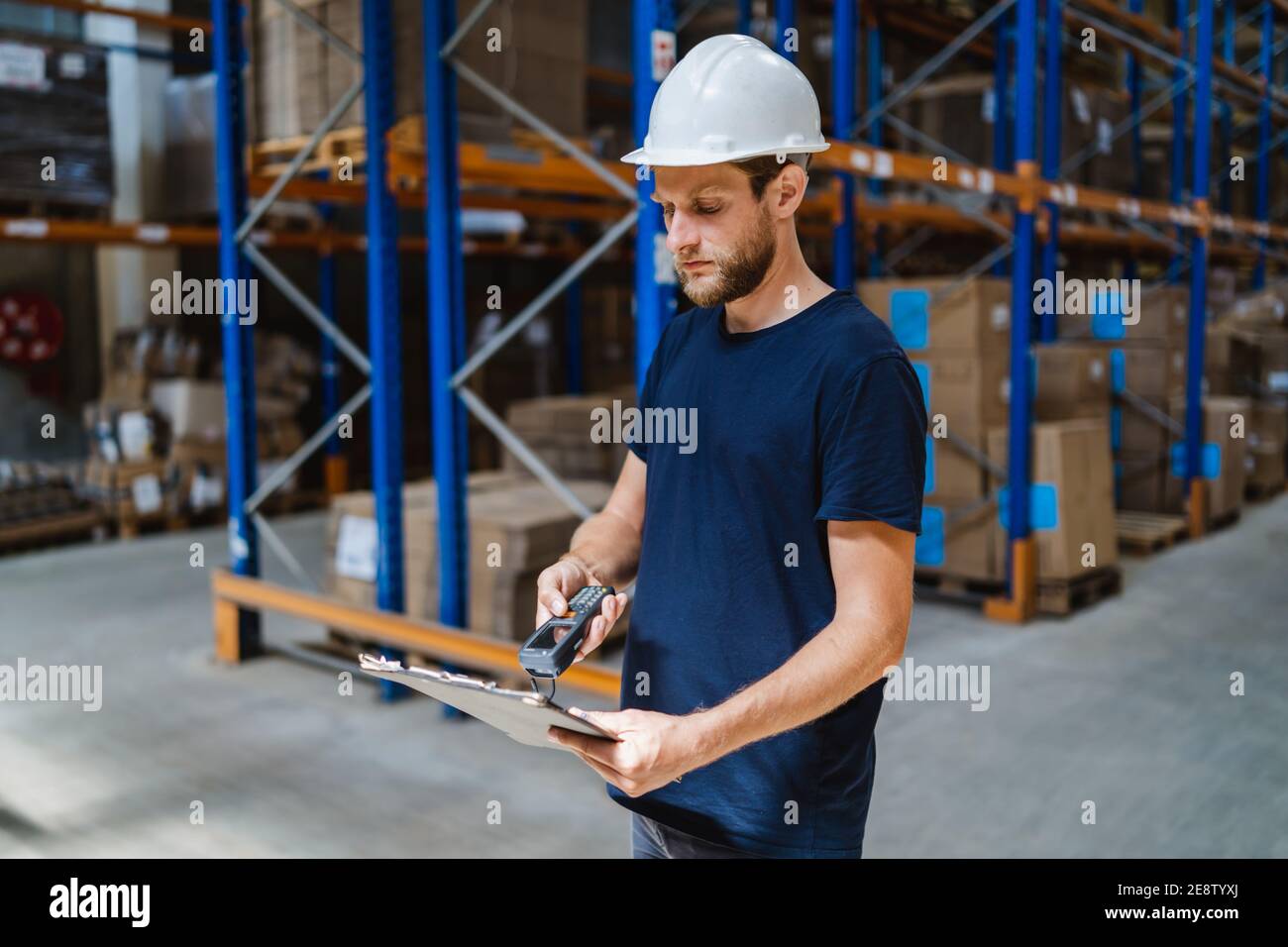 Junger Lagerleiter Warenkontrolle mit einem Clipboard in einem Lager Stockfoto