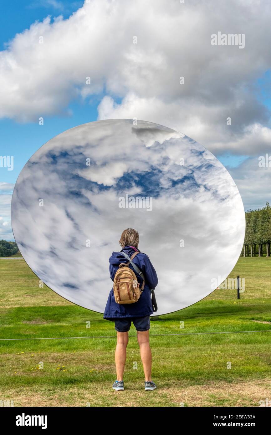 Ein Besucher, der den Sky Mirror von Anish Kapoor auf dem Gelände der Houghton Hall, Norfolk, genießt. Edelstahl, 2018. Stockfoto