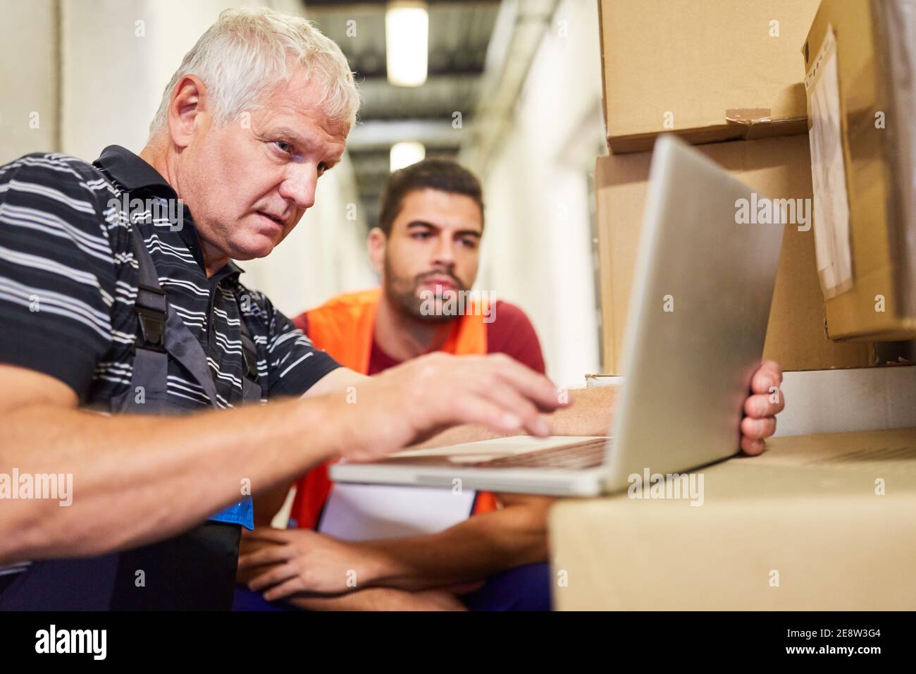 Zwei Lagerarbeiter am Laptop planen die Paketzustellung Service im Online-Handel Stockfoto