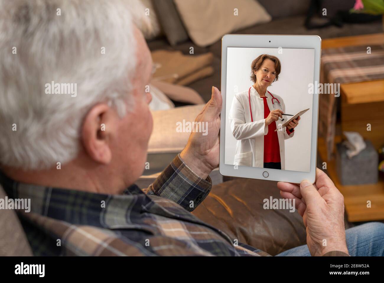 Symbolisches Bild der Telemedizin, ältere Patienten spricht mit einem Arzt in einer Videokonferenz, von zu Hause, Stockfoto