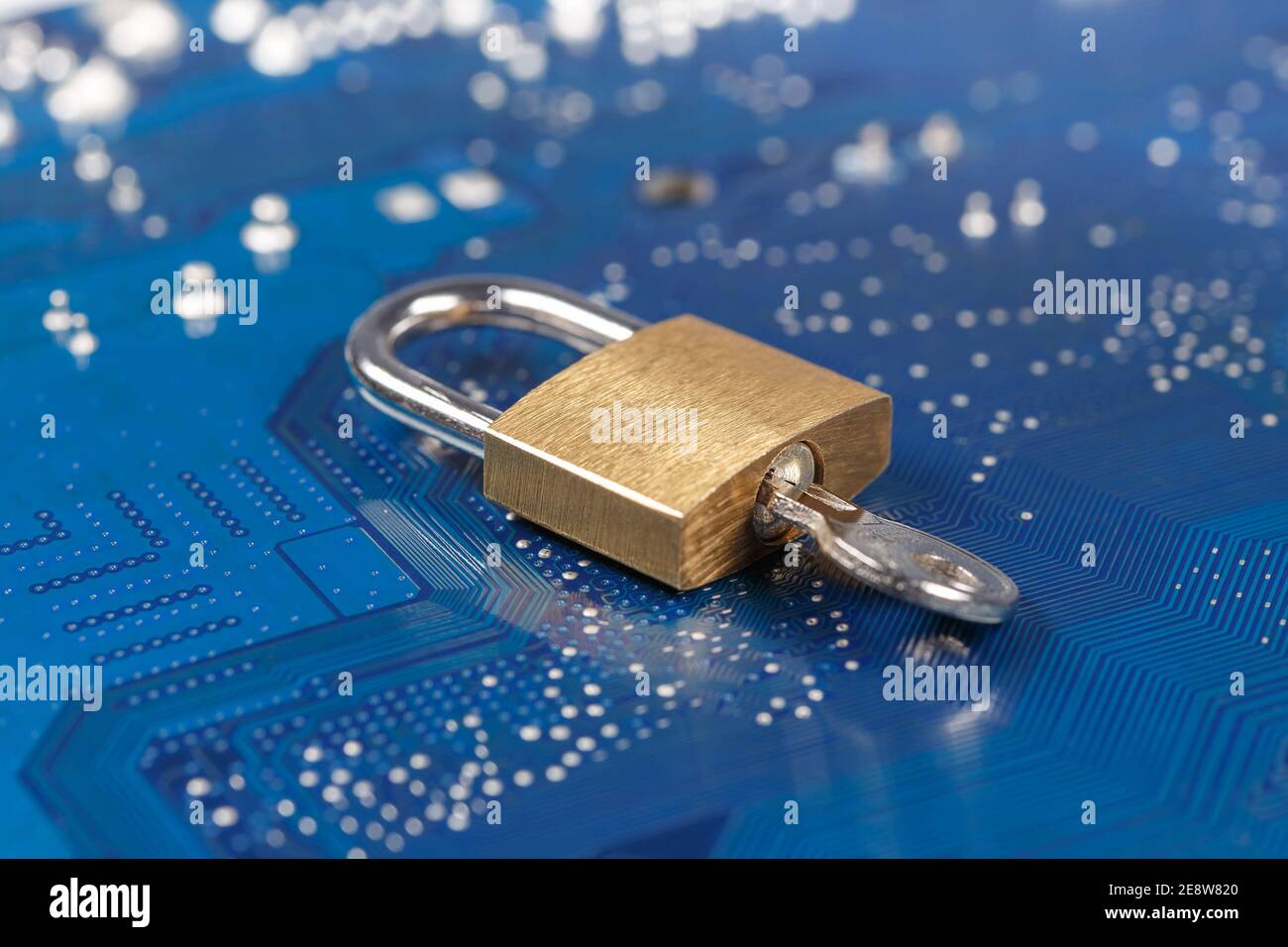 Vorhängeschloss mit Schlüssel auf blauer Leiterplatte. Das Konzept der Verschlüsselung, des Informationsschutzes, der Datensicherheit. Stockfoto