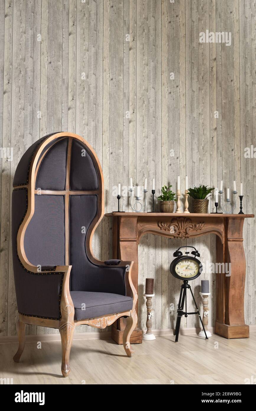Hölzerne Retro-Interieur mit großer Haube Stuhl und Kamin mit Kerzen Stockfoto