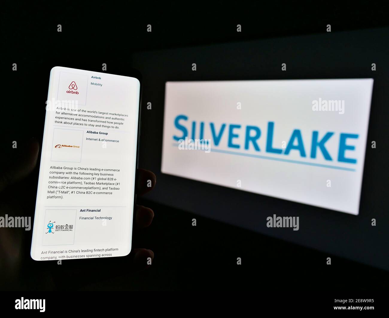 Person, die Mobiltelefon mit Website und Portfolio der US-Private-Equity-Gesellschaft Silver Lake auf dem Bildschirm vor dem Unternehmenslogo hält. Display des Fokustelefons. Stockfoto