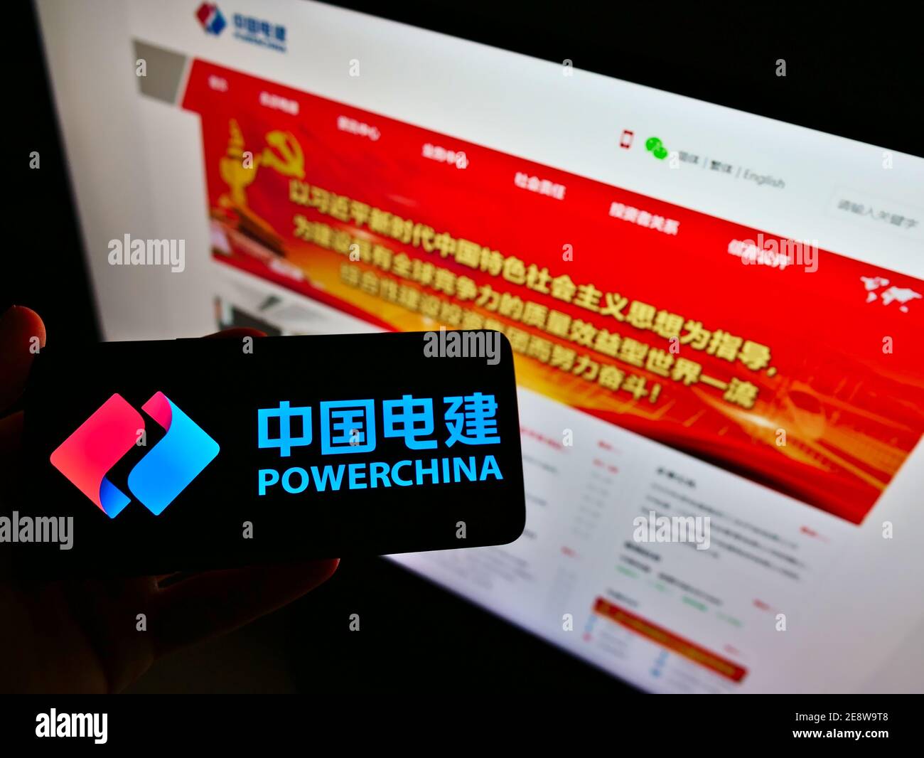 Person mit Mobiltelefon mit Logo des Ingenieurunternehmens Power Construction Corporation of China (POWERCHINA). Fokus auf Telefonbildschirm. Stockfoto
