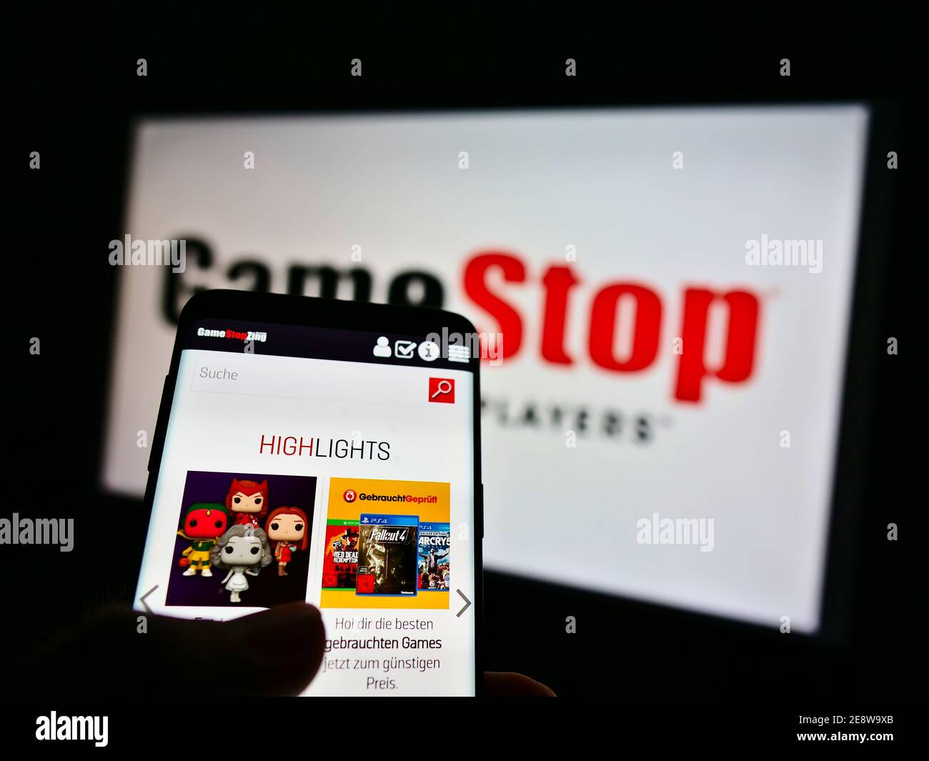 Person hält Handy mit Online-Shop des Einzelhandelsunternehmens GameStop Corp. Auf dem Display mit Business-Logo im Hintergrund. Fokus auf Telefonbildschirm. Stockfoto