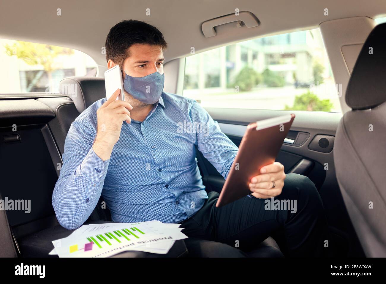 Reifer Geschäftsmann mit Gesichtsmaske arbeiten während der Reise zu Büro Stockfoto