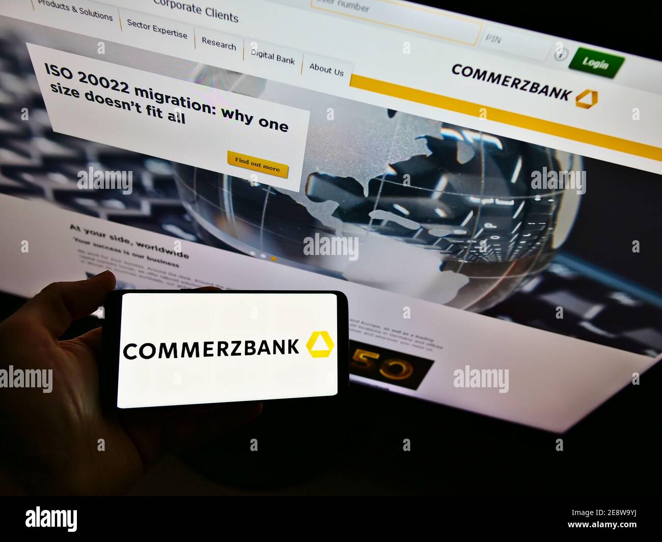 Person, die Smartphone mit Business-Logo der deutschen Universalbank Commerzbank AG auf dem Display vor der Unternehmenswebsite hält. Fokus auf Telefonbildschirm. Stockfoto