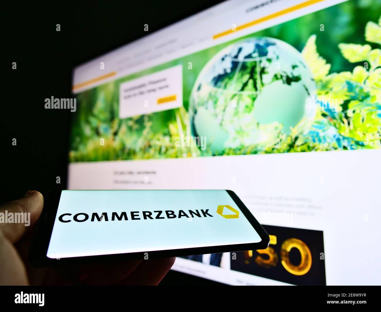 Person mit Mobiltelefon mit Firmenlogo der deutschen Bank Commerzbank AG auf dem Display vor der Webseite. Konzentrieren Sie sich auf die Mitte des Telefonbildschirms. Stockfoto