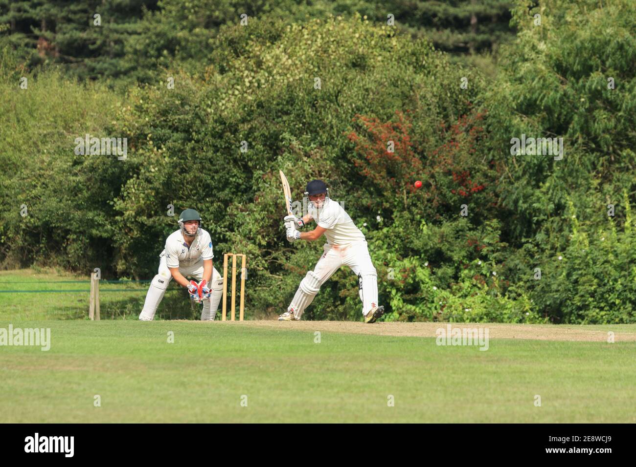 Wicket Keeper und Cricket Batsman über den Cricket-Ball zu treffen, während eines lokalen Dorf Cricket-Spiel. England GB Stockfoto