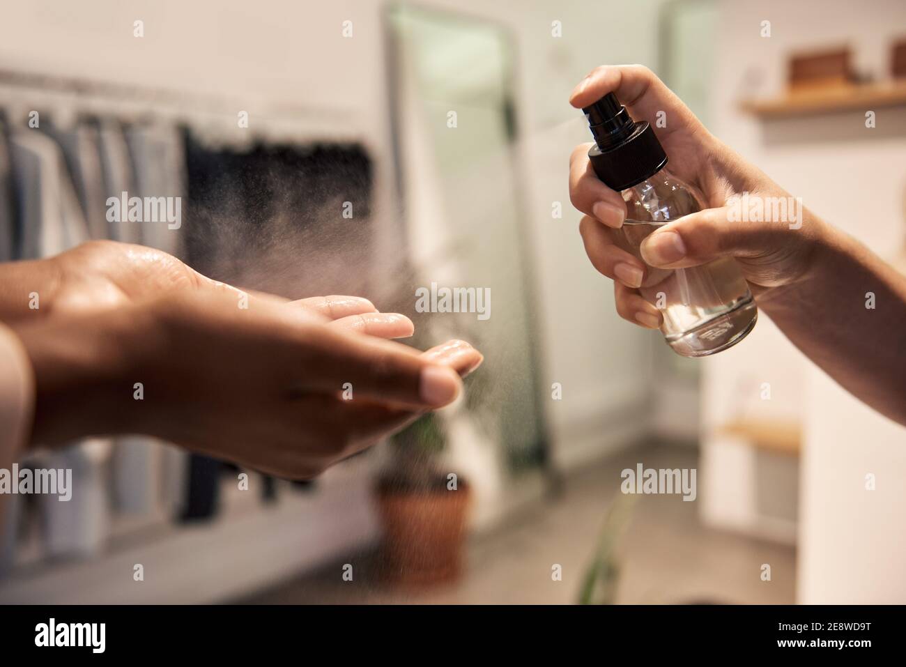Werkstattmitarbeiter, der Desinfektionsmittel auf die Hände eines Kunden aufgibt Stockfoto