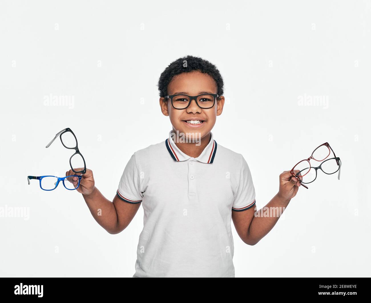 Afroamerikanischer Junge hält viele stilvolle Brillen in den Händen, für Sehkorrektur für Kinder, auf weißem Hintergrund Stockfoto