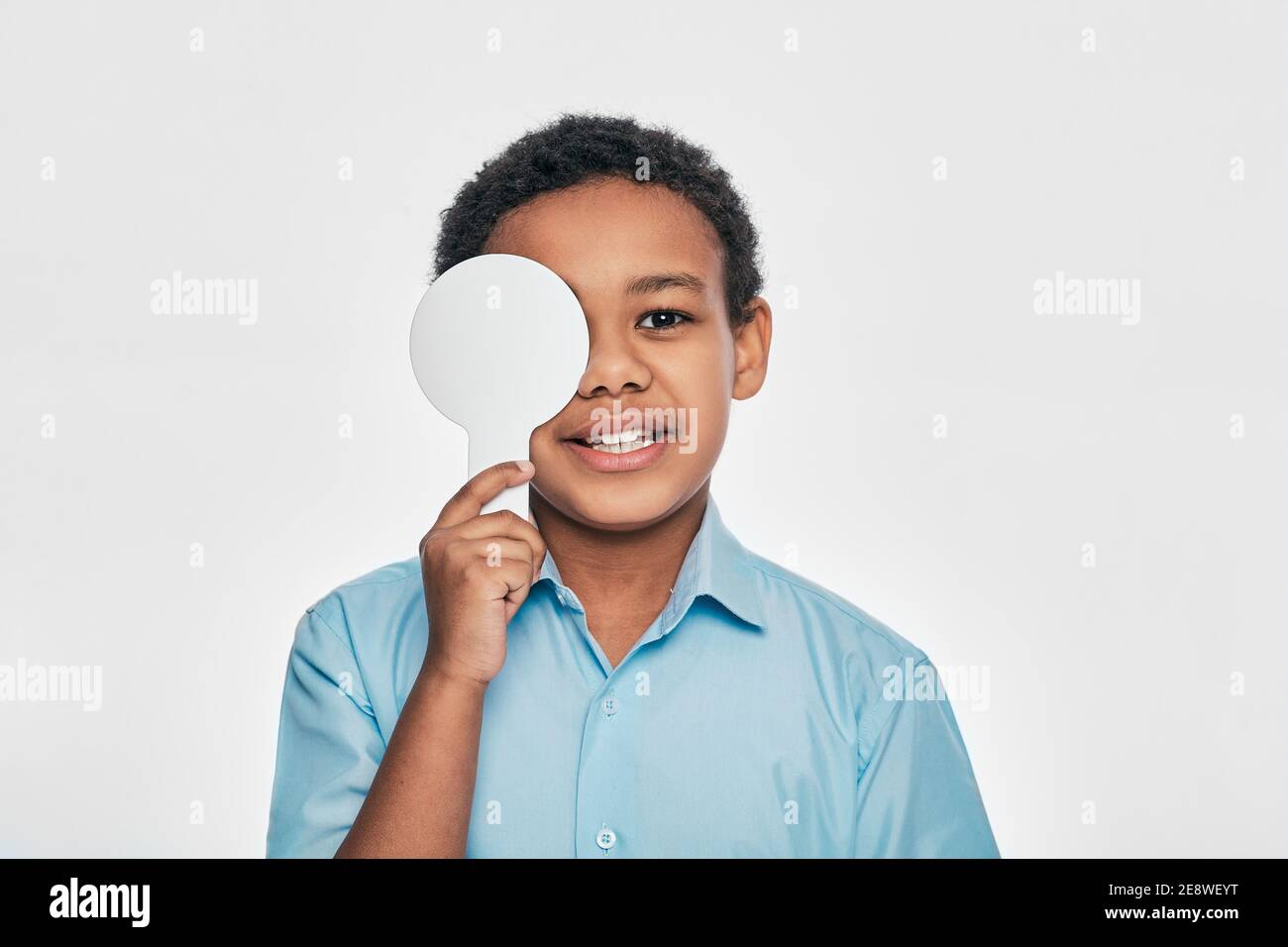 Afroamerikanische männliche Kind mit Augenuntersuchung mit einem Auge bedeckt mit einem ophthalmischen Werkzeug, auf weißem Hintergrund Stockfoto