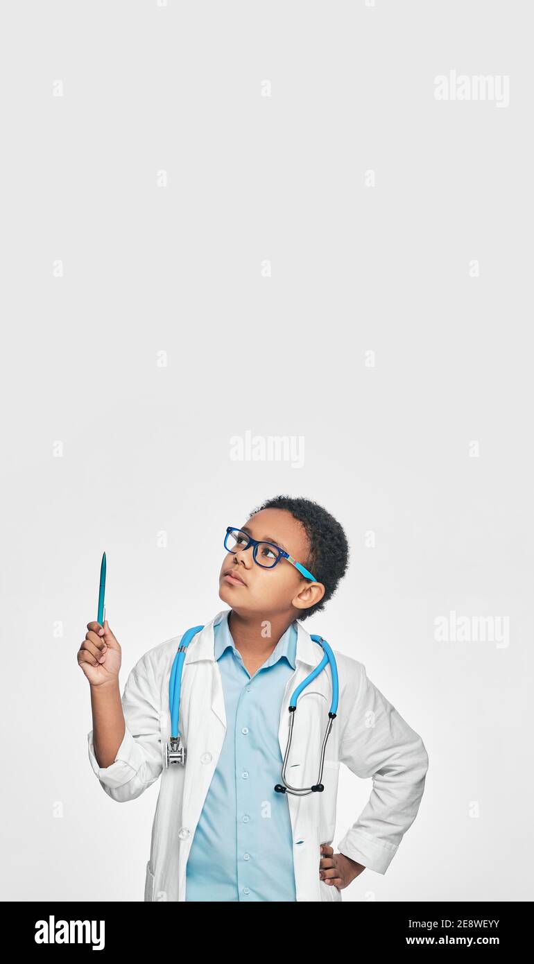 Fokussierte afroamerikanische Kind spielen Arzt, zeigt mit Stift auf leerem Raum auf weißem Hintergrund. Ort für Ihren Text, für Werbung Stockfoto