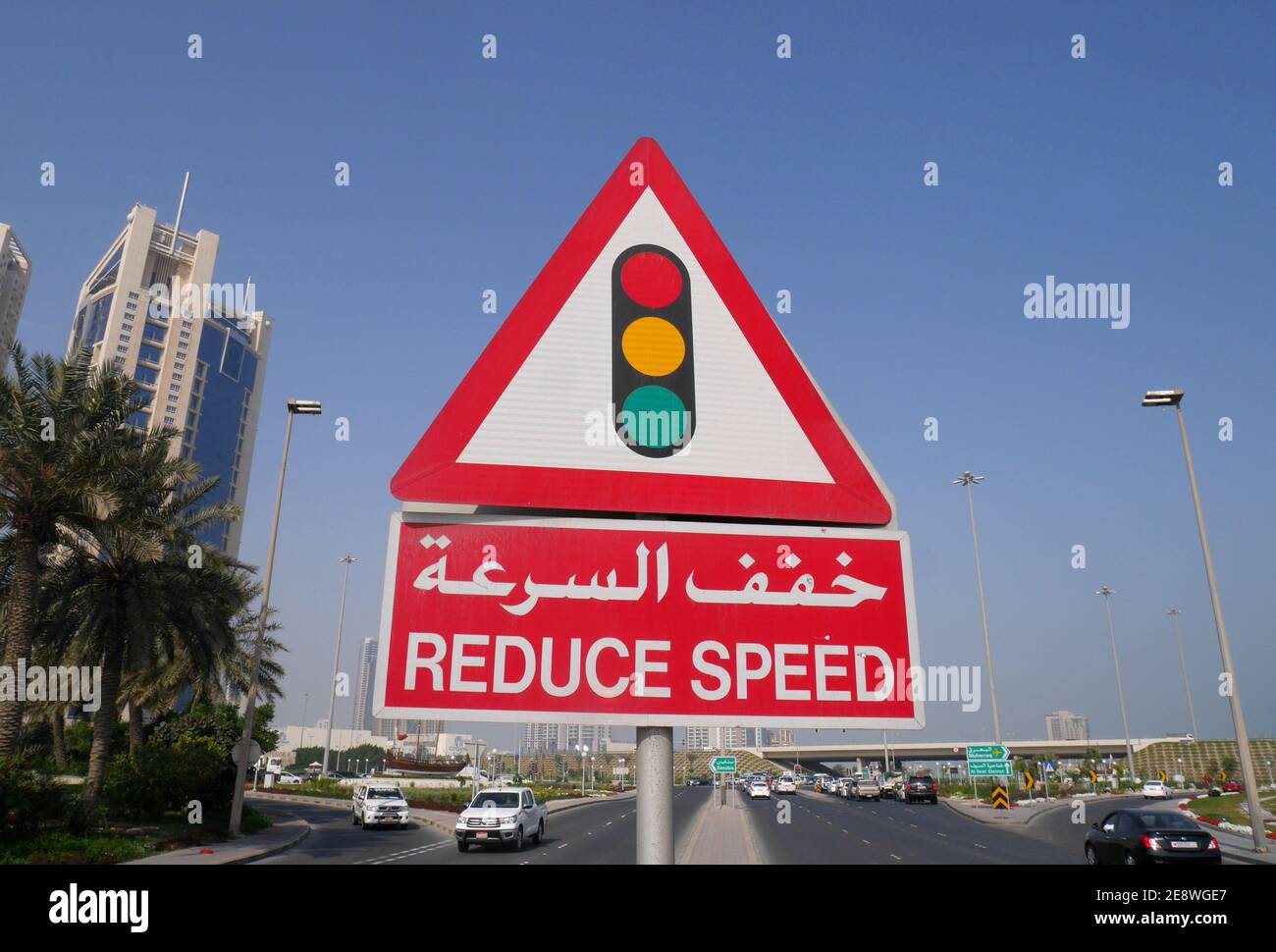 Ein Straßenschild in arabischer und englischer Sprache, das den Autofahrern sagt, dass sie wegen der Ampeln die Geschwindigkeit reduzieren sollen, Manama, Königreich Bahrain Stockfoto