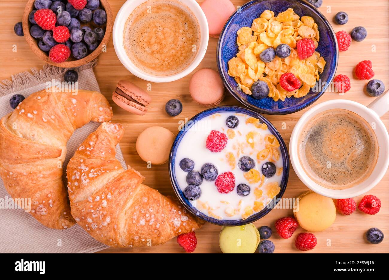 Espresso Kaffee mit Schaum, Croissants, Müsli mit Beeren und Milch. Leckeres, gesundes Frühstück. Flocken und süßes Gebäck. Hochwertige Fotos Stockfoto