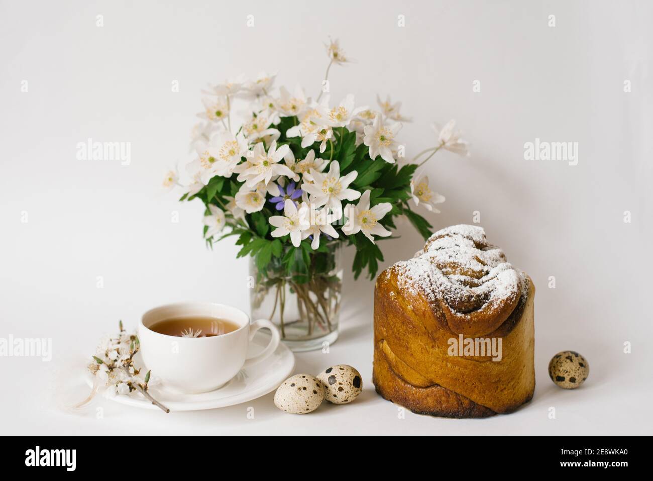 Ostern süßes Brot, Kuchen und Eier mit weißen Apfelblüten und Primeln, eine Tasse Tee. Festliches Frühstückskonzept mit Kopierfläche. Stockfoto