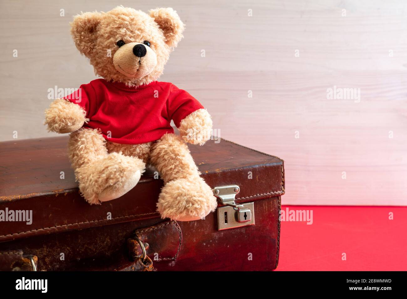 Reisen mit Kindern, verlassene Kinderkonzept. Niedlicher Teddy sitzt auf einem Vintage-Koffer. Ledergepäck im Retro-Stil in einem Kinderzimmer Stockfoto
