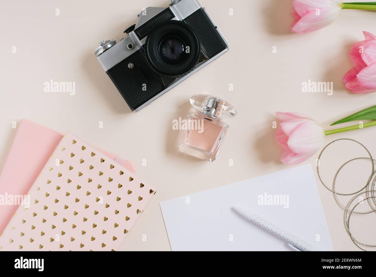 Vintage Retro-Kamera und rosa Tulpen Blumen mit leerem Notizbuch auf beigem Hintergrund. Feminine Blogger flach legen. Draufsicht. Modell für das Frühjahrskonzept. Stockfoto