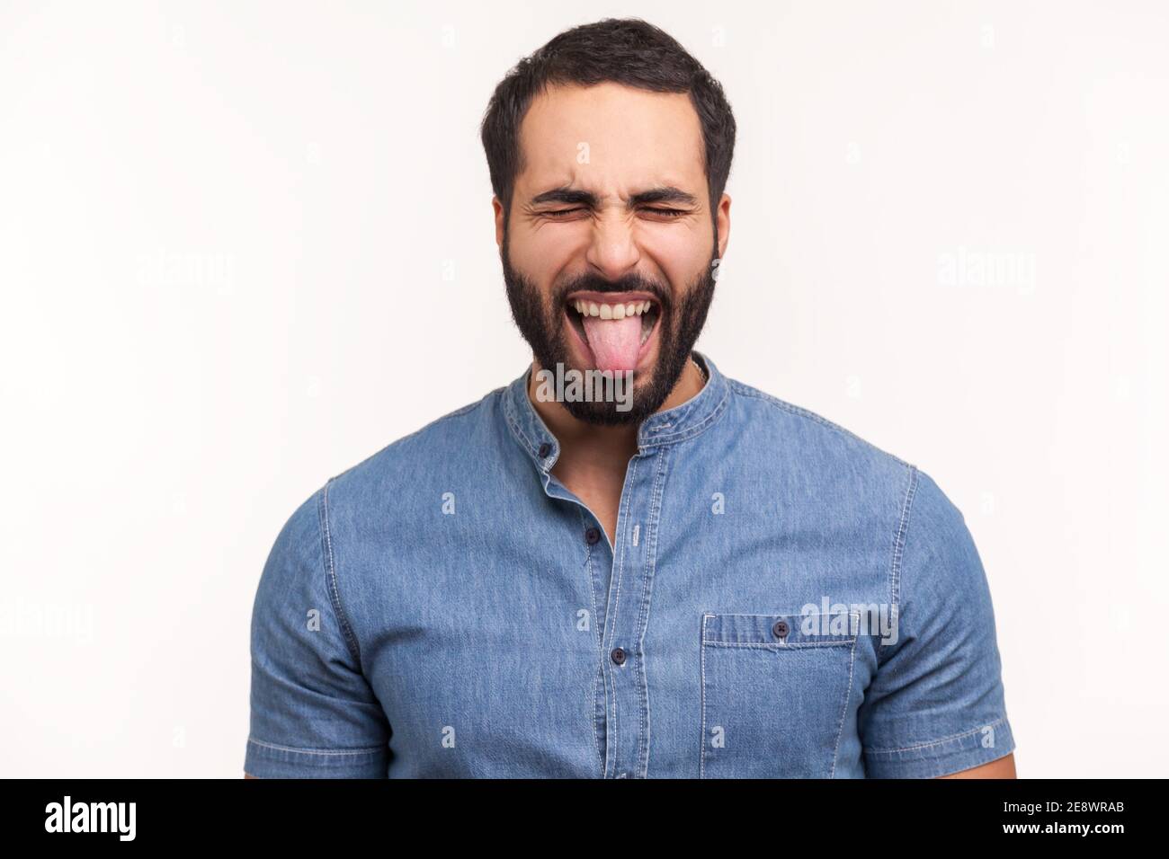 Frech infantile Mann mit Bart schließen Augen und zeigen Zunge, Spaß haben, Narren um, kindliche Manieren. Indoor Studio Shot isoliert auf weiß b Stockfoto