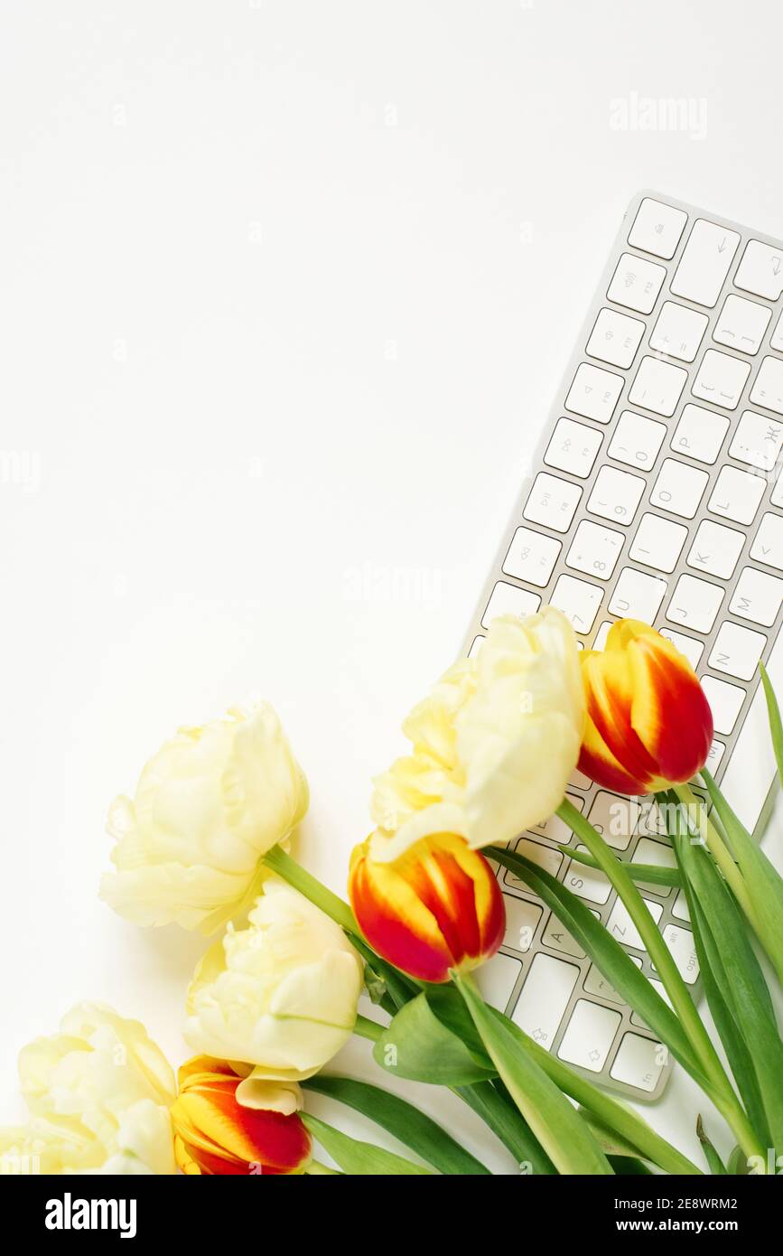 Flach liegender Valentinstag Hintergrund mit Computer-Tastatur und Tulpenstrauß. Draufsicht. Leerraum zum Kopieren Stockfoto