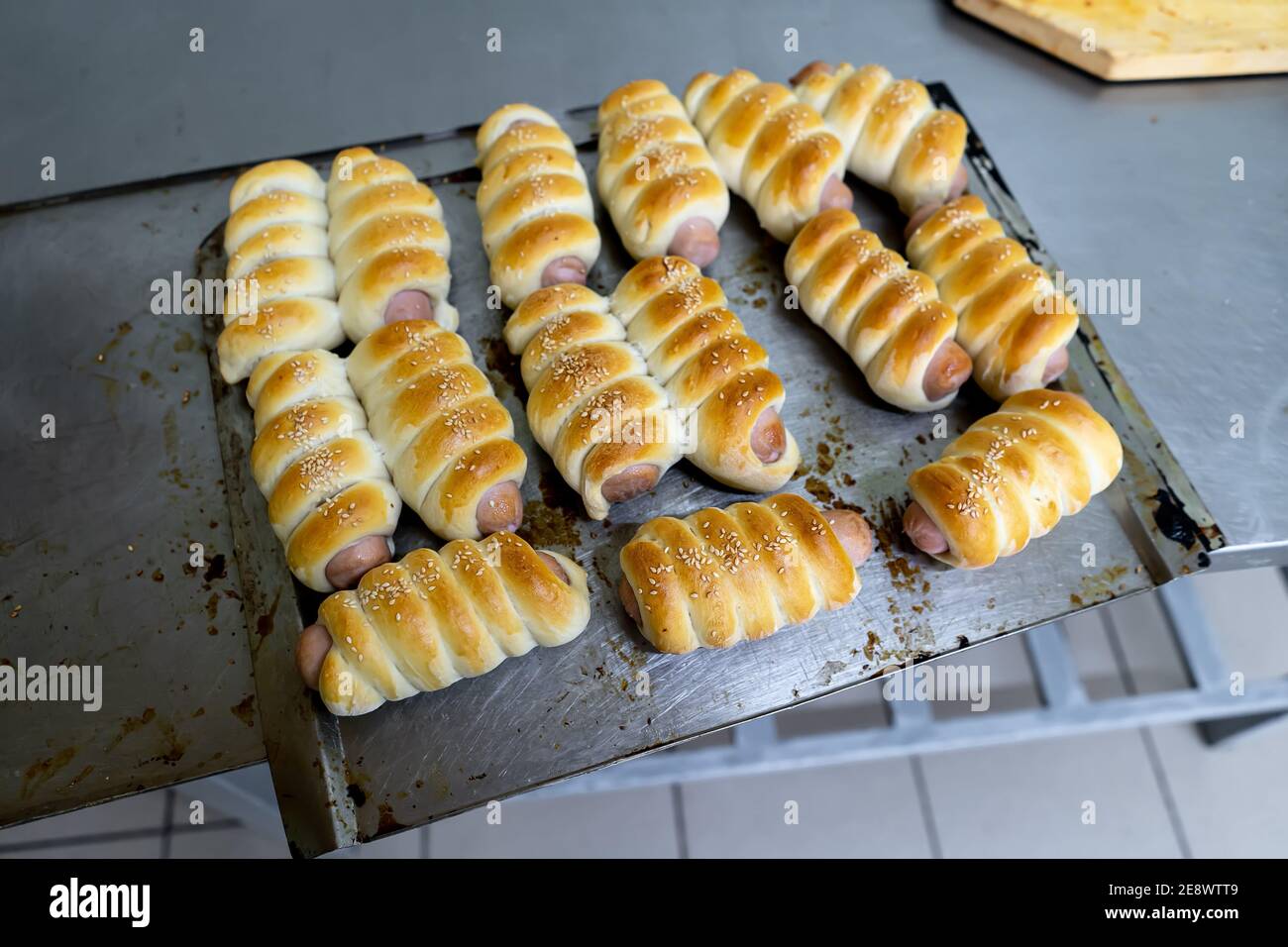 Würste im Teig auf einem Backblech. Stockfoto