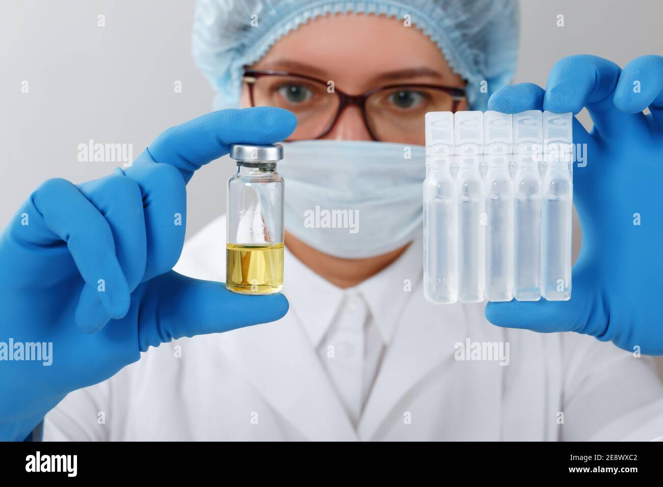 Im Labor hält eine Wissenschaftlerin mit Schutzhandschuhen und Brille Schläuche mit Proben medizinischer Tests. Stockfoto