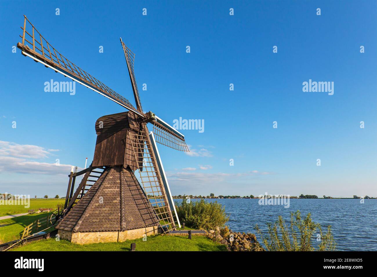 Alte hölzerne Windmühle an einem See in der niederländischen Provinz Von Friesland Stockfoto