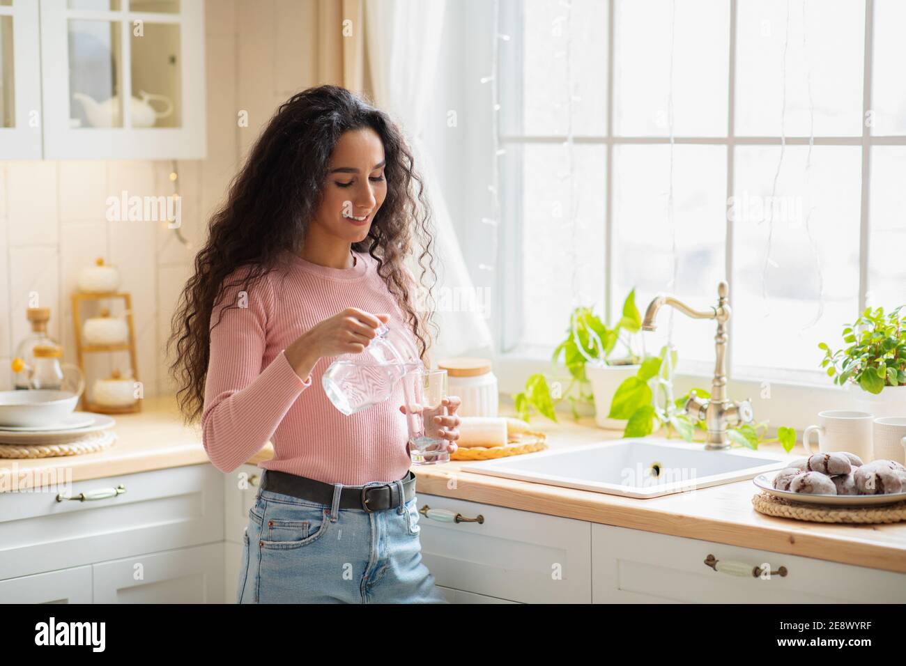 Junge Schöne Frau Trinkwasser In Küche Zu Hause Stockfoto