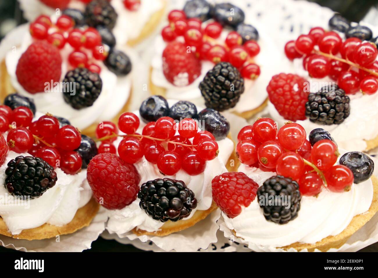 Cremige Kuchen mit frischen Beeren, Süßwarenherstellung. Süßes Dessert mit Brombeeren, Himbeeren und roten Johannisbeeren Stockfoto