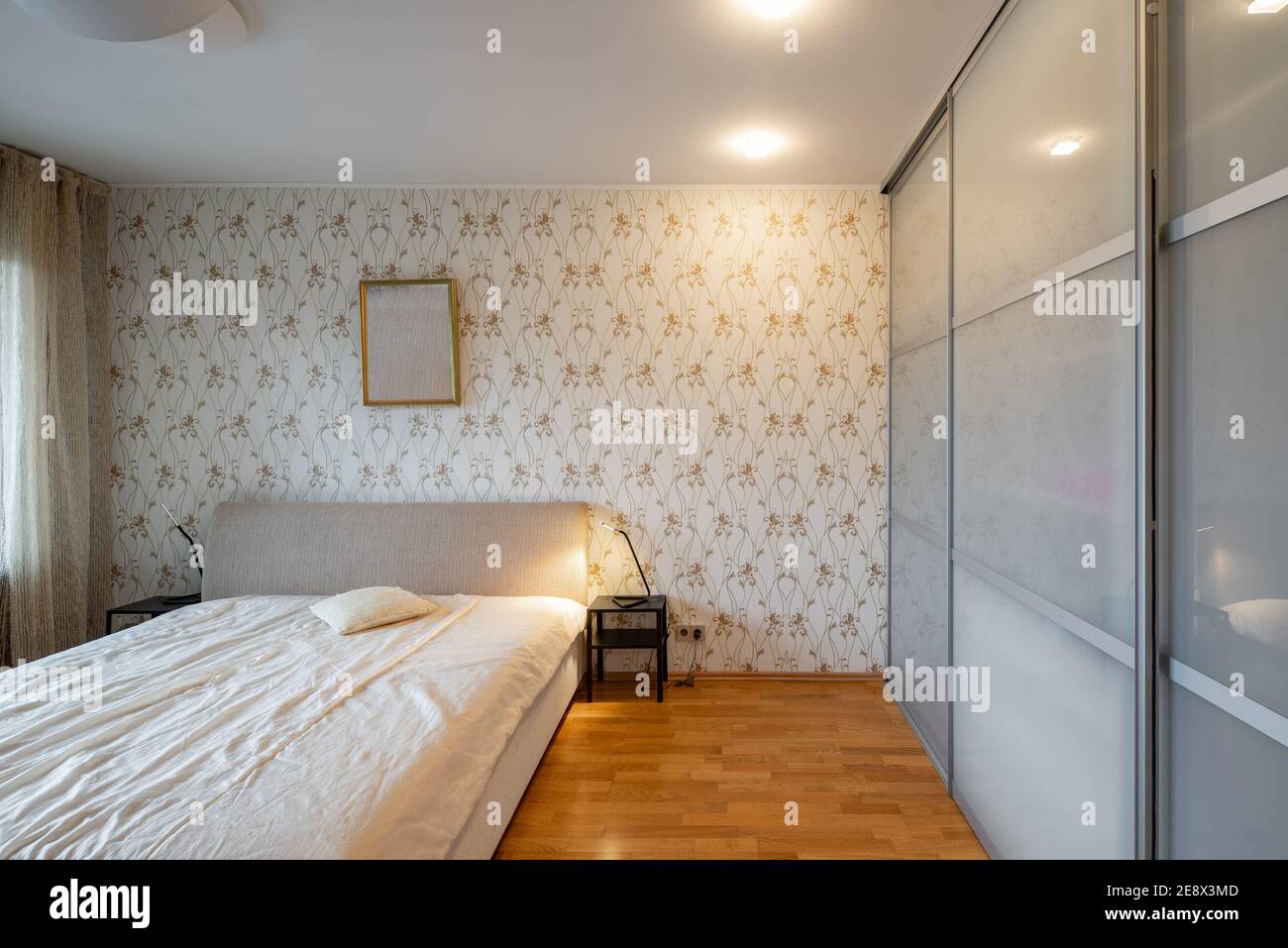 Moderne Innenausstattung des Schlafzimmers in einer Luxuswohnung.  Gemütliches Bett. Nachttische. Riesiger Schrank mit Schiebetüren  Stockfotografie - Alamy