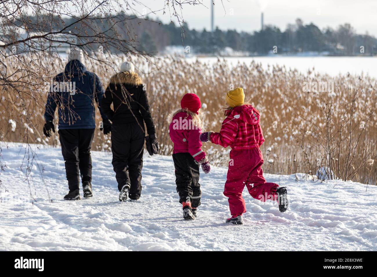 Junge Familie mit Vater, Mutter und zwei Töchtern in Winterkleidung am Sonntag Spaziergang durch gefrorene Bucht in Munkkiniemi Bezirk von Helsinki, Finnland Stockfoto
