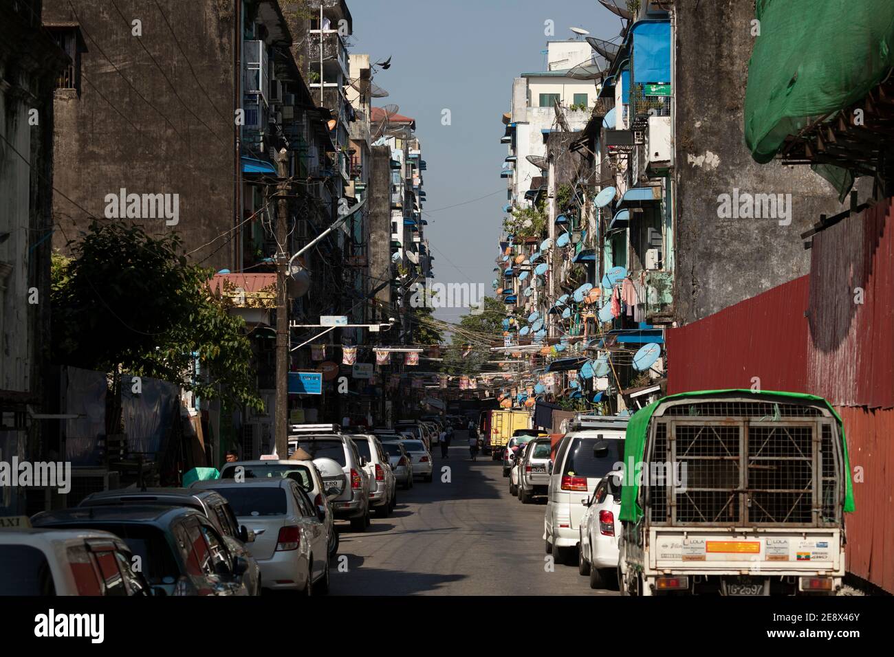 Yangon, Myanmar - 19. Dezember 2019: Haufen alter und blauer Satellitenschüsseln auf den schmutzigen Fassaden der 44th Street in der Innenstadt von Yangon, in der Nähe der belebten Straße Stockfoto