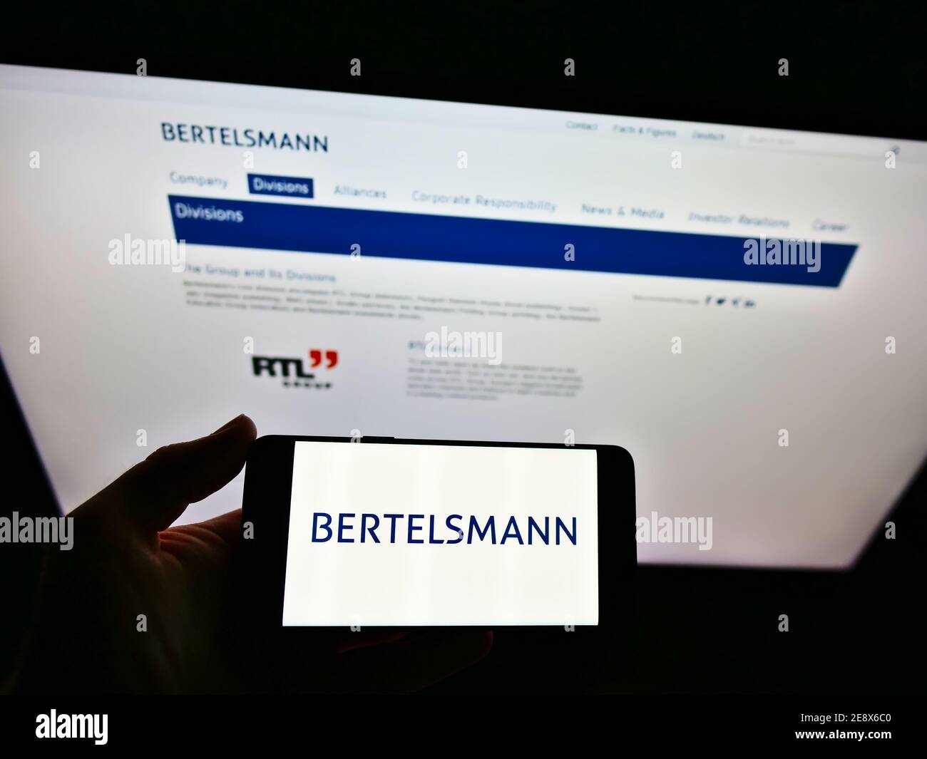 Person mit Smartphone mit Logo des deutschen Massenmedien-Konglomerats Bertelsmann vor der Website. Konzentrieren Sie sich auf den Bildschirm des Mobiltelefons. Stockfoto