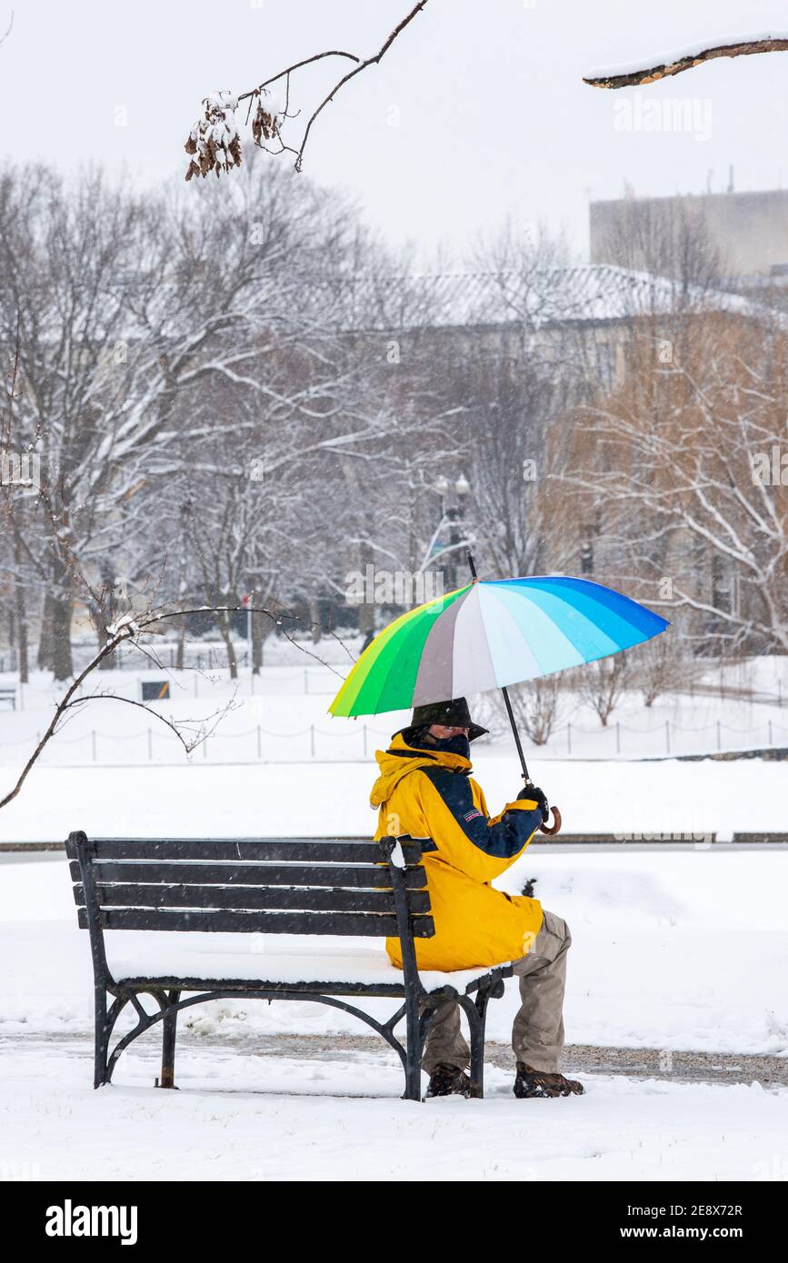 Ein Mann mit einem bunten Regenschirm besucht Constitution Gardens während eines verschneiten Tages in Washington, D.C. Stockfoto