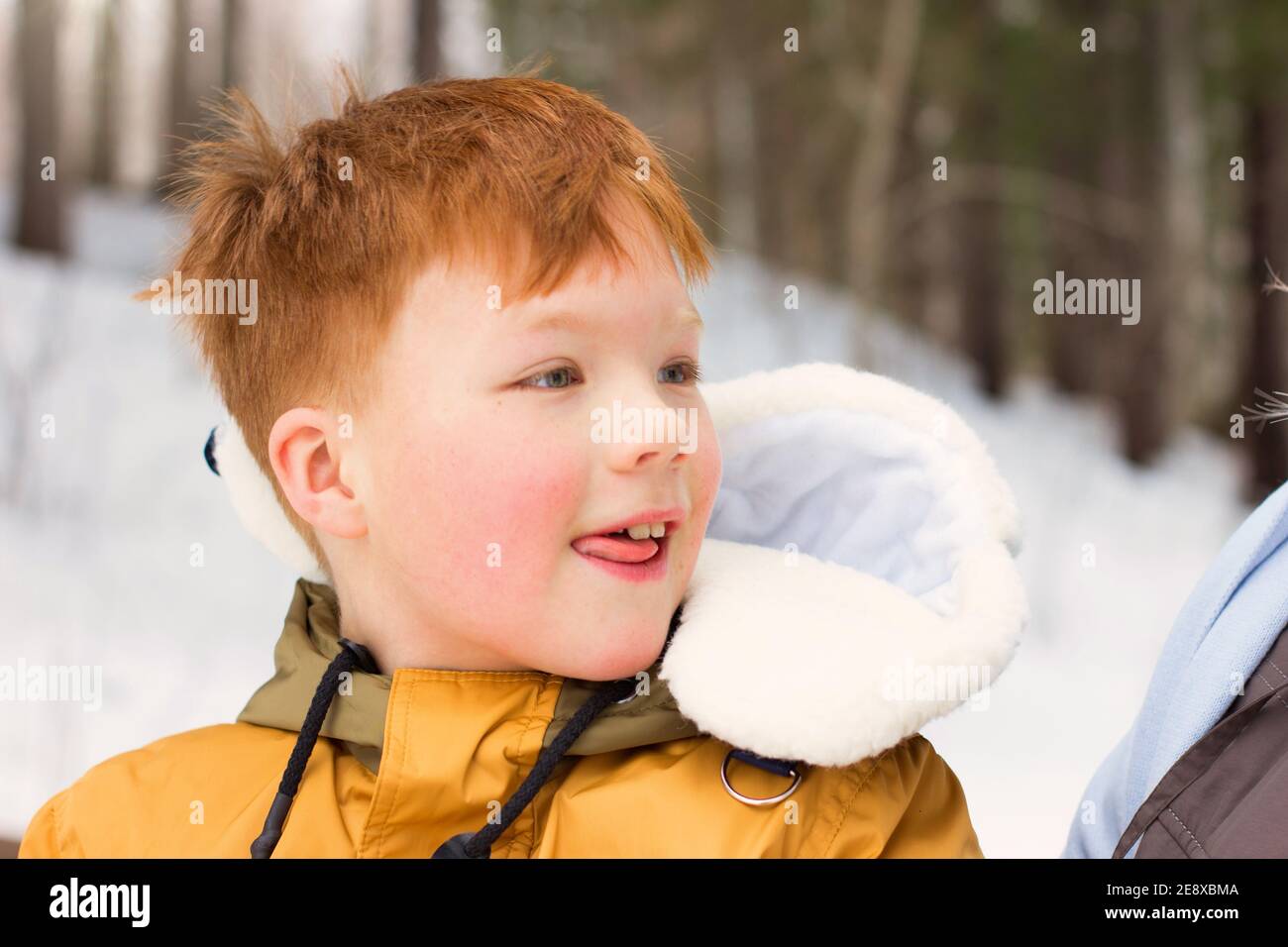 Rot behaart Junge zeigt Zunge. Nette positive Junge mit blauen Augen im Freien. Spielen im Wald und Walking-Konzept. Selektiver Fokus. Stockfoto