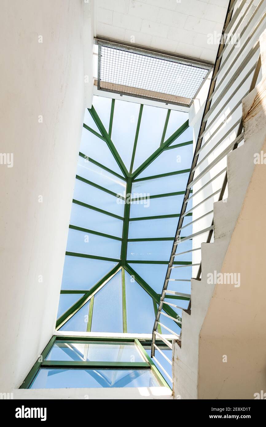 Oberseite der Betontreppe mit weißen Wänden und grün Die Handschiene auf dem modernen, sauberen, mehrstöckigen Parkplatz sah nach oben aus Zum Oberlicht an hellen sonnigen Tag Stockfoto