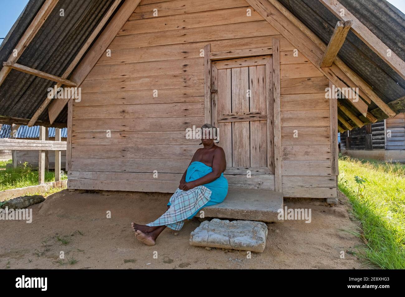Afro-Suriname Frau posiert vor einem Holzhaus im Dorf Aurora, Bezirk Sipaliwini, Surinam / Surinam Stockfoto
