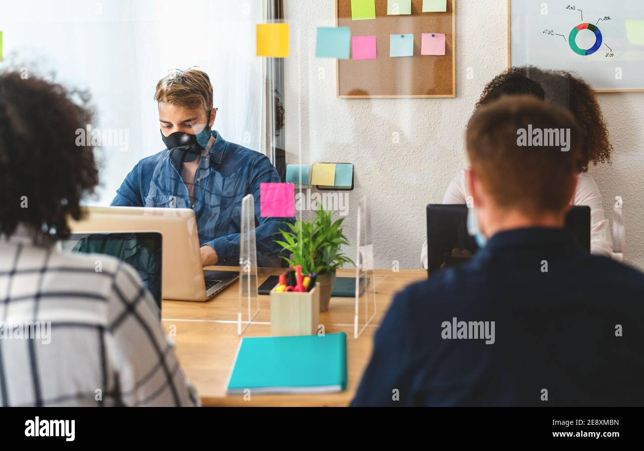 Junge Menschen in Co-Working kreativen Raum tragen chirurgische Maske und Soziale Distanz halten, um die Verbreitung des Corona-Virus zu vermeiden Stockfoto