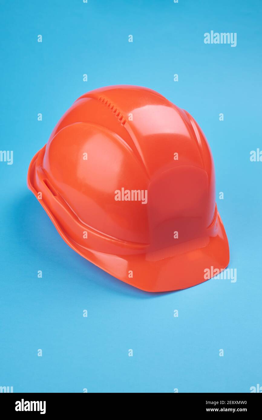 Orangefarbener Schutzhelm und Schutzbrille in der Nähe auf hellblauem Hintergrund. Schutzkleidung und Bauindustrie Konzept Stockfoto